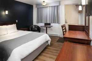 拉图克Hôtel Marineau Centre的配有一张床和一张书桌的酒店客房