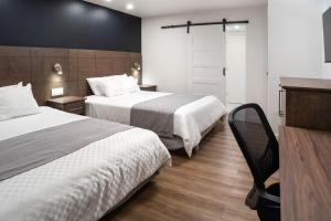 拉图克Hôtel Marineau Centre的酒店客房配有两张床和一张书桌