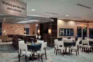 萨凡纳萨凡纳机场希尔顿逸林酒店的一间带桌椅的餐厅和一间酒吧