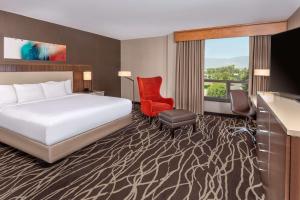 圣贝纳迪诺圣贝纳迪诺希尔顿逸林酒店的酒店客房,配有一张床和一张红色椅子