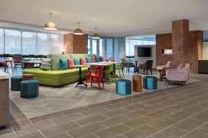 刘易斯Home2 Suites By Hilton Lewes Rehoboth Beach的大堂设有绿色的沙发和桌椅