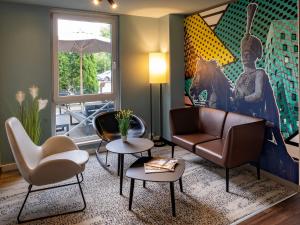 汉诺威B&B Hotel Hannover-Lahe的客厅配有沙发、椅子和绘画作品