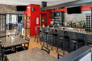 拉图克Hôtel Marineau La Tuque的餐厅里设有红色墙壁和凳子的酒吧