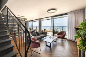 海法Stunning 2BR Apartment with Balcony and Ocean View in the Heart of Haifa by Sea N' Rent的带沙发和椅子的客厅以及楼梯。