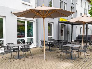 汉诺威B&B Hotel Hannover-Lahe的一组桌椅和一把伞