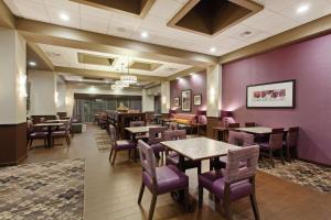 埃弗里特西雅图汉普顿酒店/埃弗里特市中心的餐厅设有木桌、椅子和紫色墙壁