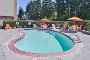 西塔科西雅图机场汉普顿酒店的一个带椅子和遮阳伞的小型游泳池