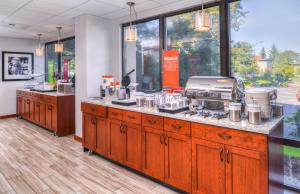 西塔科西雅图机场汉普顿酒店的厨房配有木制橱柜和带电器的台面。