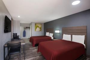 布达布达美式超值旅馆的酒店客房带两张床和一张桌子以及椅子。