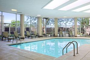布里奇顿Embassy Suites by Hilton St Louis Airport的大楼内一个带桌椅的游泳池