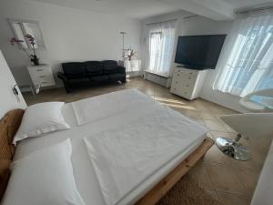 梅尔斯堡Hotel la Perla的卧室配有白色的床和电视。