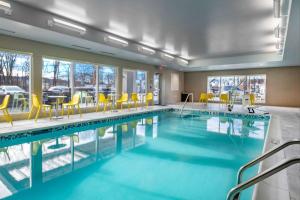 韦恩Home2 Suites By Hilton Wayne, NJ的一座游泳池,里面设有黄色的椅子和桌子