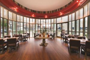 塔斯卡卢萨Embassy Suites by Hilton Tuscaloosa Alabama Downtown的餐厅设有桌椅和大窗户。