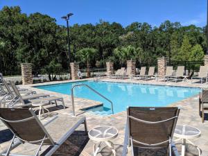 卫斯理堂Hilton Garden Inn Tampa - Wesley Chapel的一个带椅子和桌子的大型游泳池