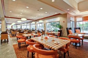 渥太华渥太华机场希尔顿花园酒店的餐厅设有木桌、椅子和窗户。