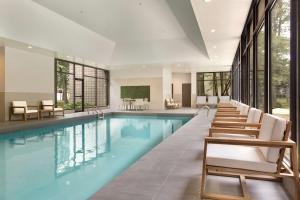 米西索加希尔顿逸林酒店多伦多机场西店的一个带椅子和桌子的游泳池