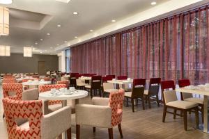 米西索加希尔顿逸林酒店多伦多机场西店的用餐室配有桌椅和窗帘