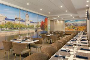 潘特克莱尔蒙特利尔机场希尔顿大使馆套房酒店 的一间设有桌椅的餐厅,并拥有城市壁画