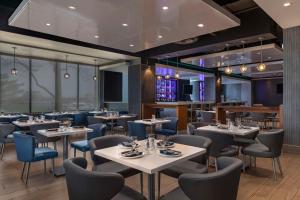 多伦多多伦多机场希尔顿大使馆套房酒店的餐厅设有白色的桌子和蓝色的椅子