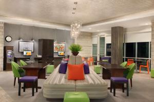 奥斯汀希尔顿Home2套房酒店 - 得克萨斯州奥斯汀北/靠近the Domain购物中心的客房设有桌椅和一张带色彩缤纷枕头的床。
