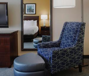本顿维尔本顿维尔希尔顿逸林套房酒店的一间卧室配有一张床、一把椅子和镜子
