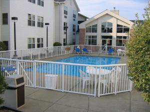 独立市克利夫兰汉普顿独立套房酒店的游泳池周围的白色围栏,配有桌椅