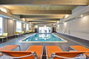 杰克逊Home 2 Suites By Hilton Jackson的一座游泳池,位于酒店客房内,配有橙色椅子