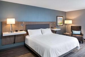 恩菲尔德哈利法克斯机场希尔顿花园酒店的卧室配有一张白色大床和一把椅子