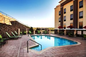 塔尔萨塔尔萨/塔尔萨山汉普顿酒店及套房 的一座带桌椅的游泳池位于酒店大楼旁