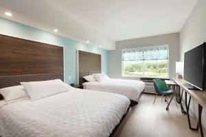 查尔斯湖Tru By Hilton Lake Charles的一间卧室设有两张床、一张桌子和一个窗口。