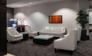 温尼伯温尼伯机场希尔顿套房酒店的一间设有白色椅子和电视的等候室