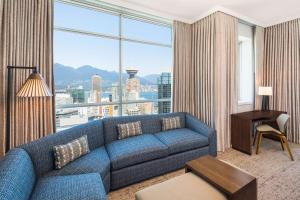 温哥华Hilton Vancouver Downtown, BC, Canada的客厅设有蓝色的沙发和大窗户