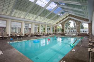 南乌特南诺特希尔顿逸林酒店 的一个带椅子和玻璃天花板的大型游泳池