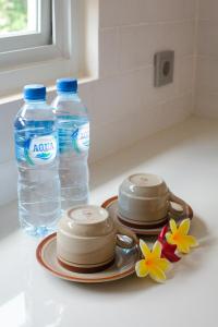 金巴兰Donguri House Bali的2瓶水和1盘花在柜台上的花