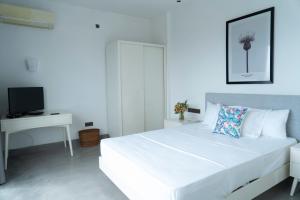 科伦坡Four Petals Inn的白色的卧室配有一张白色的大床和一张书桌