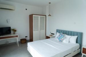 科伦坡Four Petals Inn的卧室配有白色的床和电视。