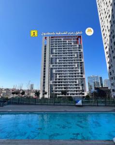 伊斯坦布尔ZamZam Suites Istanbul的一座高大的建筑,前面有一个游泳池