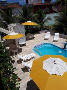 塔曼达雷Flat Porto dos Carneiros的一个带遮阳伞和椅子的游泳池以及一个游泳池