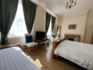 凯恩舍姆Manor Lodge Guesthouse的一间卧室配有一张床、一张书桌和一台电视。