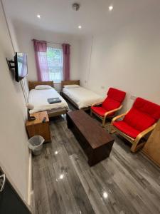 特伦特河畔斯托克Zams rooms的一间设有两张床和两张红色椅子的房间
