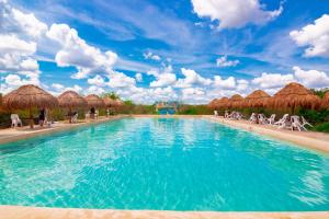 HomúnCabañas Santa Cruz Homún的度假酒店的游泳池配有椅子和草伞