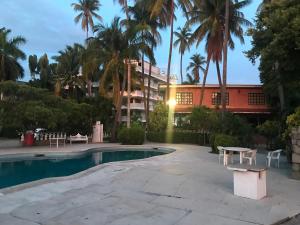 阿卡普尔科Hotel las hamacas的一个带桌子的游泳池和一座建筑