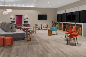 卡尔斯巴德Home2 Suites By Hilton Carlsbad New Mexico的一间设有五颜六色的椅子和桌子的等候室