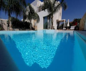 马尔扎梅米La Perla di Marzamemi的一座房子前面的蓝色海水游泳池