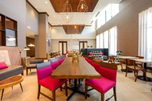 奥罗拉Hampton Inn & Suites Aurora South, Co的用餐室配有粉红色的椅子和桌子