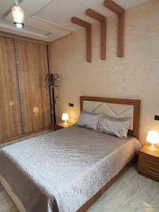 梅克内斯Appartement Dar Meknès的一间卧室配有一张带两张桌子和两盏灯的床。