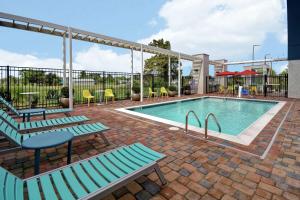 哈维Home2 Suites by Hilton Harvey New Orleans Westbank的游泳池设有2个长椅和桌椅