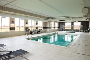 里贾纳里贾纳东门汉普顿套房酒店的大楼内带桌椅的大型游泳池
