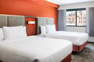 达拉斯达拉斯市区/西端万豪春季山丘套房酒店的橙色墙壁的酒店客房内的两张床