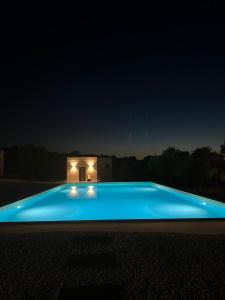 多尔加利Agriturismo La Croisette的蓝色的游泳池,在晚上有房子在后面